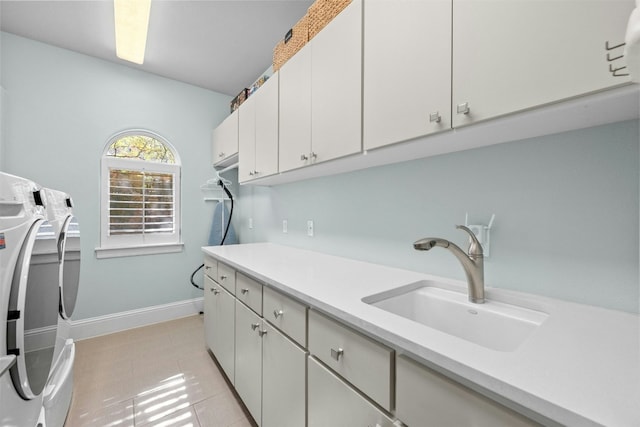 laundry room featuring washing machine and clothes dryer, light tile patterned floors, cabinets, and sink