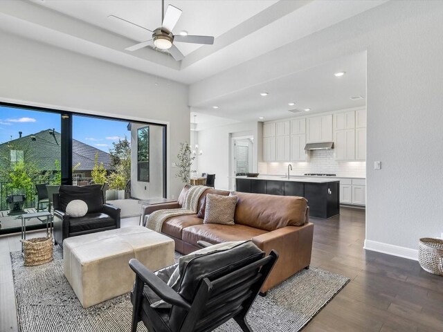 living room featuring dark hardwood / wood-style flooring, ceiling fan, and sink