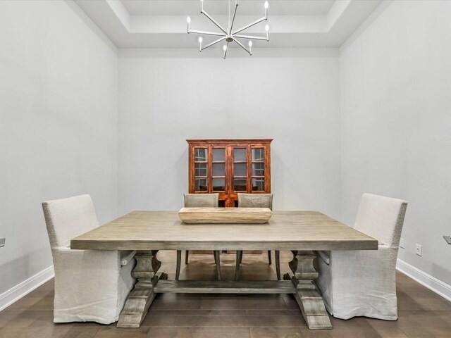 dining room featuring a raised ceiling, dark hardwood / wood-style flooring, and a chandelier