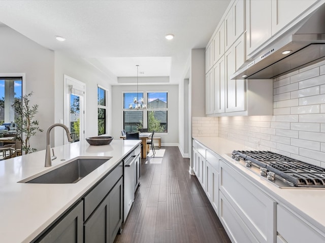 kitchen with ventilation hood, sink, dark hardwood / wood-style floors, white cabinetry, and hanging light fixtures