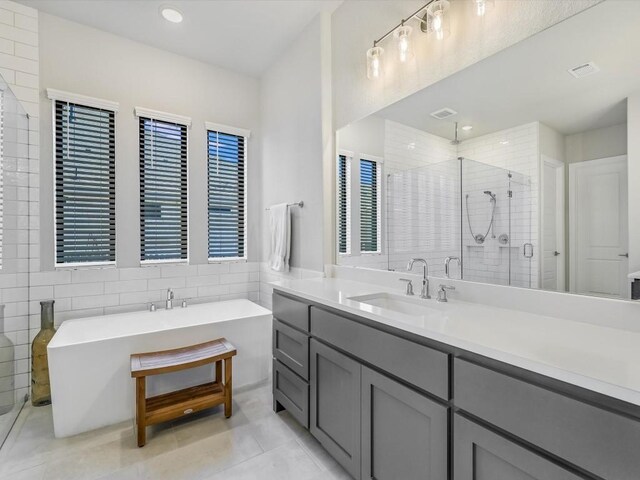 bathroom featuring tile patterned flooring, vanity, tile walls, and independent shower and bath