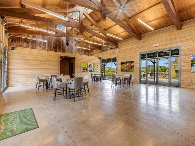 dining room with concrete flooring, beamed ceiling, high vaulted ceiling, and a healthy amount of sunlight