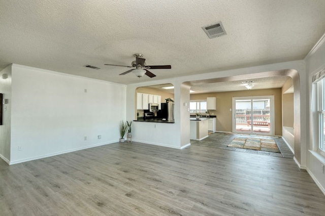 unfurnished living room featuring visible vents, ceiling fan, and light wood finished floors