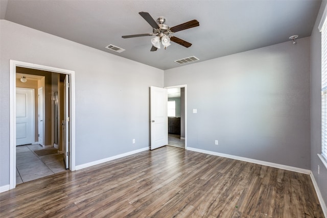 unfurnished bedroom with ceiling fan and dark wood-type flooring