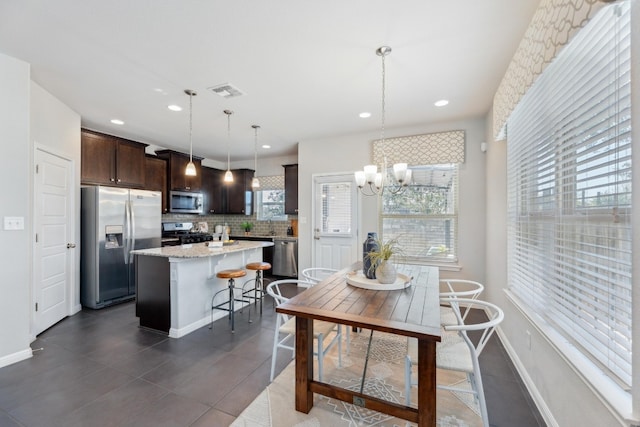 kitchen featuring dark brown cabinetry, a kitchen island, decorative light fixtures, stainless steel appliances, and a breakfast bar