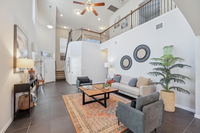 living room featuring ceiling fan, dark tile patterned flooring, and a towering ceiling