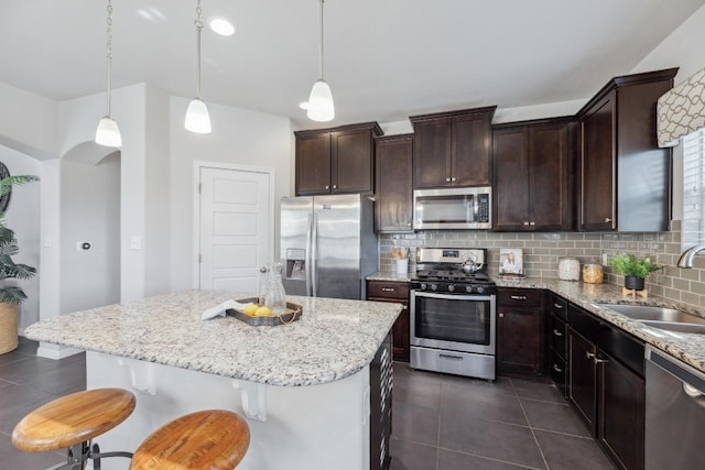 kitchen featuring decorative light fixtures, sink, appliances with stainless steel finishes, and a center island