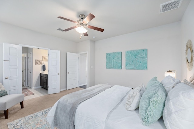 bedroom with ceiling fan, light carpet, and ensuite bath