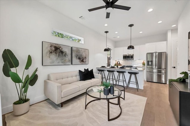 living room featuring ceiling fan and light hardwood / wood-style floors