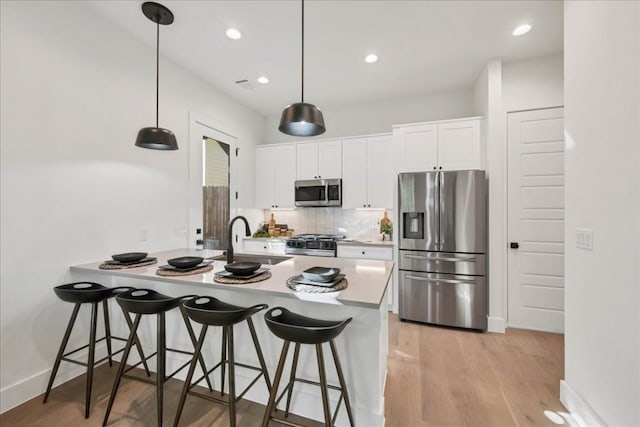 kitchen with white cabinetry, stainless steel appliances, decorative light fixtures, and sink