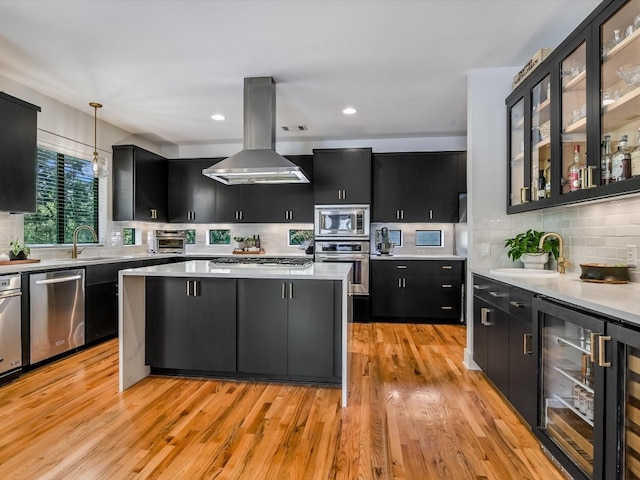 kitchen featuring pendant lighting, wine cooler, light hardwood / wood-style flooring, appliances with stainless steel finishes, and island exhaust hood