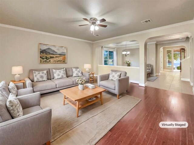 living room featuring ornamental molding, ceiling fan with notable chandelier, and light wood-type flooring