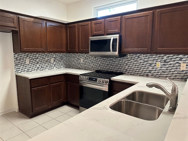 kitchen featuring light stone countertops, sink, stainless steel appliances, decorative backsplash, and light tile patterned flooring