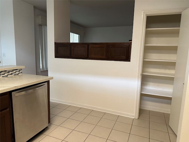 kitchen featuring dark brown cabinets, light tile patterned floors, and stainless steel dishwasher