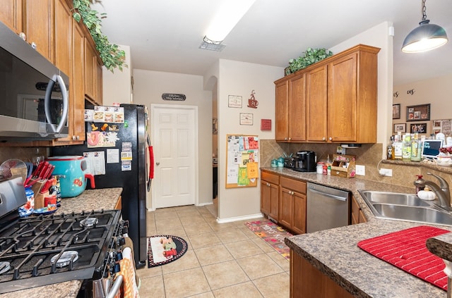 kitchen featuring backsplash, sink, hanging light fixtures, light tile patterned floors, and appliances with stainless steel finishes