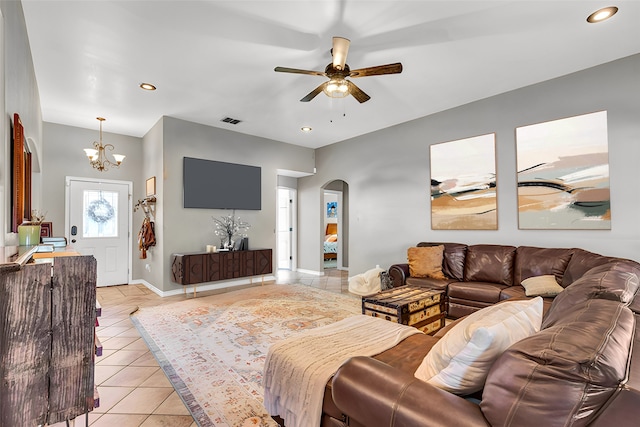 tiled living room with ceiling fan with notable chandelier