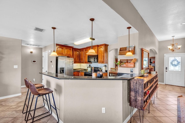 kitchen with kitchen peninsula, pendant lighting, light tile patterned floors, black appliances, and an inviting chandelier