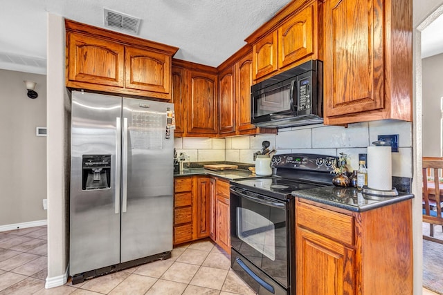 kitchen featuring a textured ceiling, light tile patterned flooring, dark stone countertops, tasteful backsplash, and black appliances