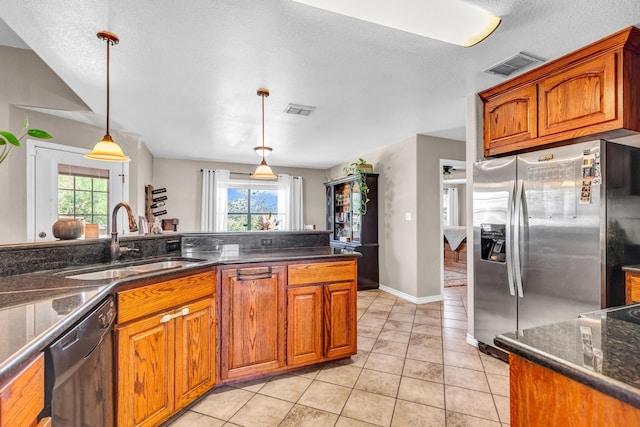 kitchen featuring sink, decorative light fixtures, black dishwasher, light tile patterned flooring, and stainless steel fridge