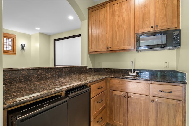 kitchen with dishwasher, dark stone countertops, and sink