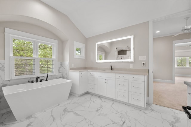 bathroom featuring vanity, a tub to relax in, a wealth of natural light, and lofted ceiling