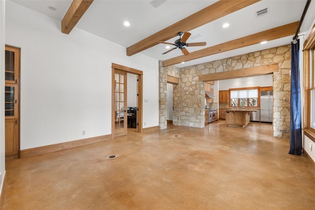 unfurnished living room featuring ceiling fan and beamed ceiling