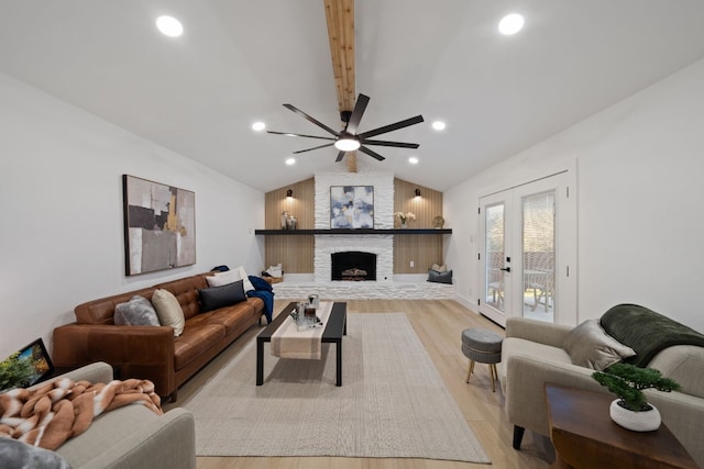 living room featuring a fireplace, lofted ceiling with beams, french doors, and light wood-type flooring