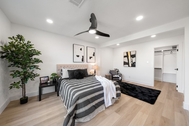 bedroom with ceiling fan, a spacious closet, and light wood-type flooring