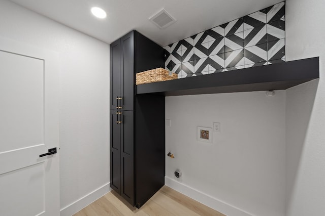 clothes washing area featuring washer hookup, cabinets, and light hardwood / wood-style flooring