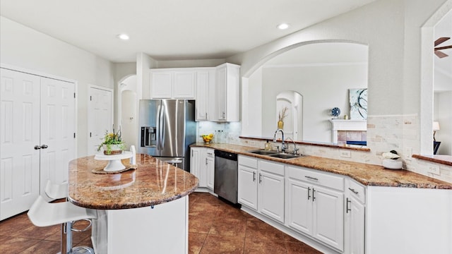 kitchen with kitchen peninsula, sink, white cabinets, and appliances with stainless steel finishes