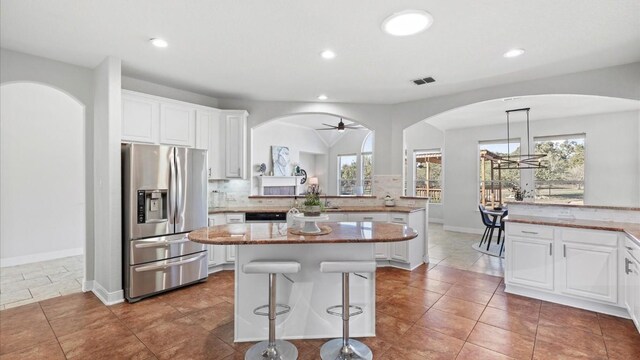 kitchen featuring light stone countertops, stainless steel fridge with ice dispenser, a kitchen island, and a wealth of natural light