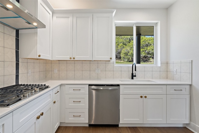 kitchen with stainless steel appliances, sink, wall chimney range hood, light hardwood / wood-style flooring, and white cabinetry