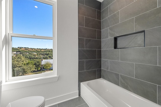 bathroom featuring tile patterned floors, tiled shower / bath combo, toilet, and a wealth of natural light