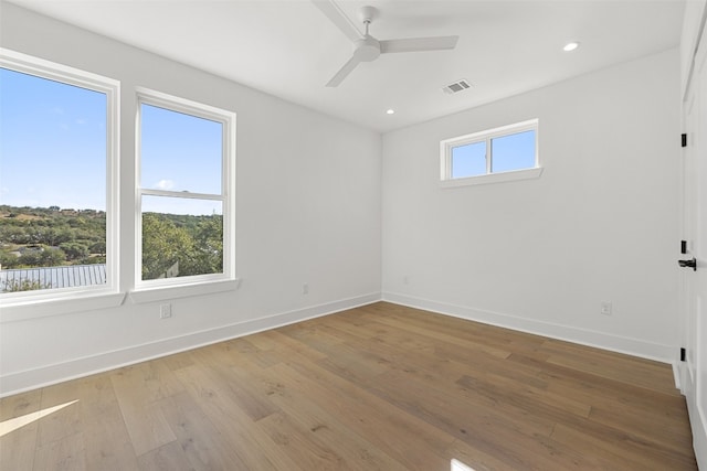 spare room featuring ceiling fan, a healthy amount of sunlight, and light wood-type flooring