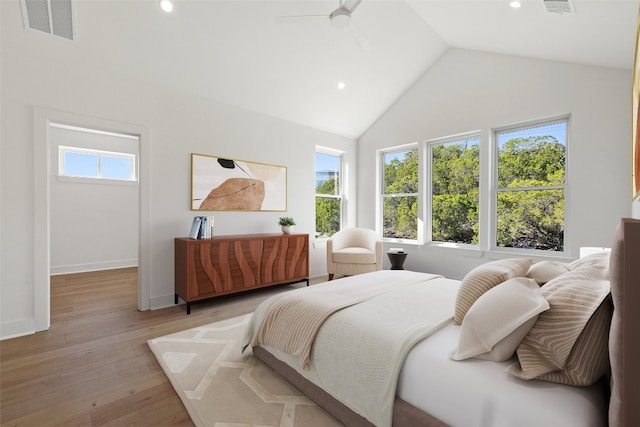 bedroom featuring multiple windows, light hardwood / wood-style floors, high vaulted ceiling, and ceiling fan