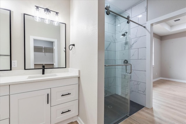 bathroom with wood-type flooring, a shower with door, and vanity