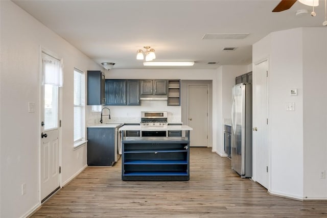 kitchen with sink, light hardwood / wood-style flooring, ceiling fan, a kitchen island, and stainless steel appliances