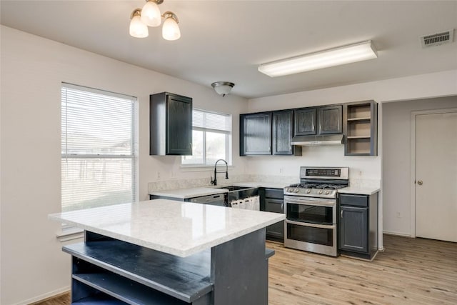 kitchen with light stone countertops, sink, light hardwood / wood-style flooring, range with two ovens, and a kitchen island