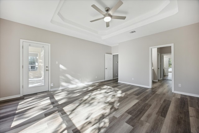 spare room with dark hardwood / wood-style flooring, a tray ceiling, and a wealth of natural light