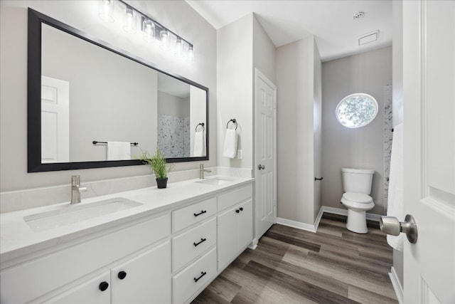 bathroom featuring a shower, hardwood / wood-style floors, vanity, and toilet