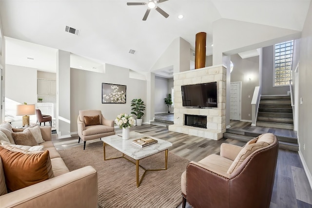 living room featuring a stone fireplace, ceiling fan, high vaulted ceiling, and hardwood / wood-style flooring