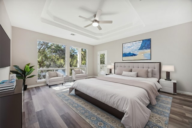 bedroom featuring ceiling fan, dark hardwood / wood-style flooring, and a raised ceiling