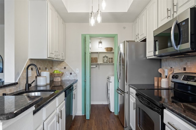 kitchen with sink, white cabinetry, hanging light fixtures, stainless steel appliances, and washer and clothes dryer