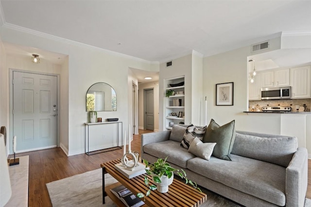 living room with dark hardwood / wood-style floors, ornamental molding, and built in shelves