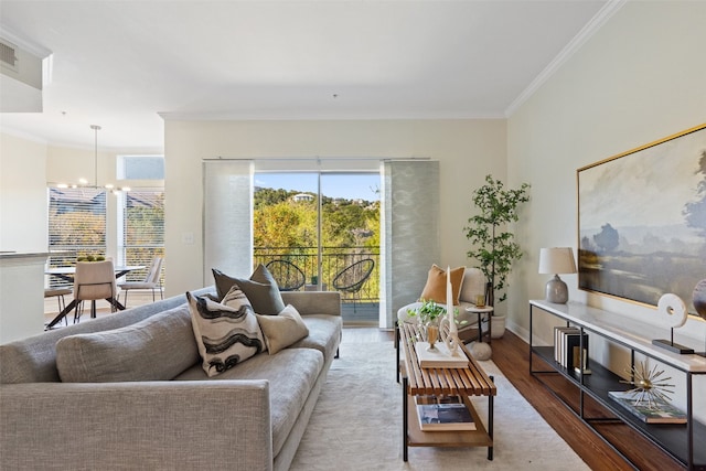 living room featuring wood-type flooring, plenty of natural light, an inviting chandelier, and crown molding