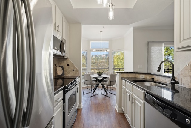 kitchen featuring sink, hanging light fixtures, dark hardwood / wood-style flooring, stainless steel appliances, and white cabinets