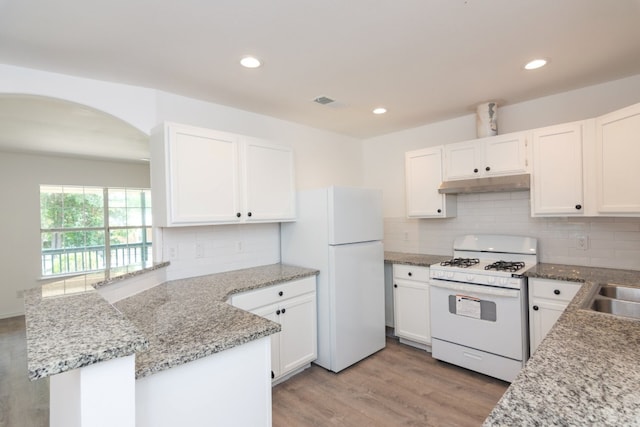 kitchen featuring white cabinetry, backsplash, kitchen peninsula, white appliances, and light wood-type flooring