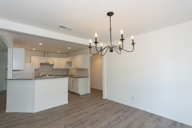 kitchen featuring hardwood / wood-style floors, white appliances, an inviting chandelier, and white cabinetry