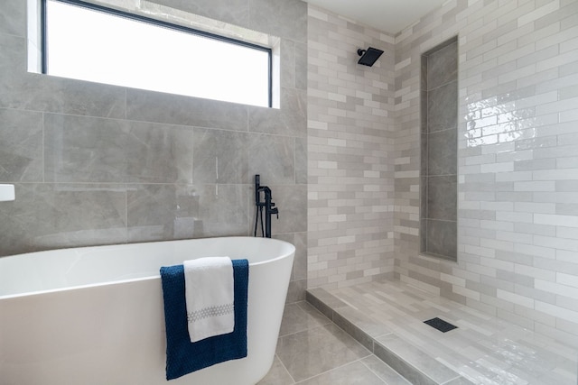 bathroom featuring tile patterned floors, separate shower and tub, and tile walls