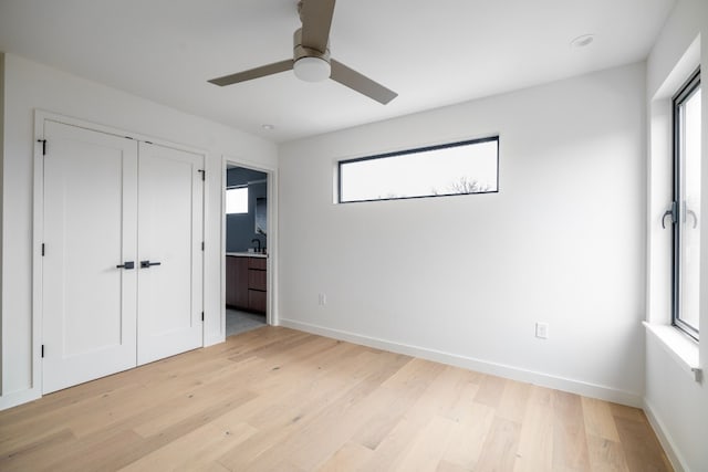 unfurnished bedroom with a closet, multiple windows, ceiling fan, and light hardwood / wood-style flooring